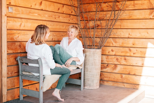 Mujeres en jeans y blusas blancas charlando sobre fondo de madera