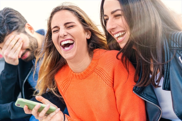 Foto mujeres jóvenes alegres con teléfonos inteligentes disfrutando al aire libre