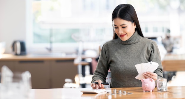 Mujeres jóvenes asiáticas que trabajan con papeles financieros en casa cuentan con la calculadora para planificar el presupuesto para la economía y ahorrar dinero