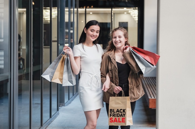 Mujeres jóvenes asiáticas y de raza mixta que llevan bolsas de compras,