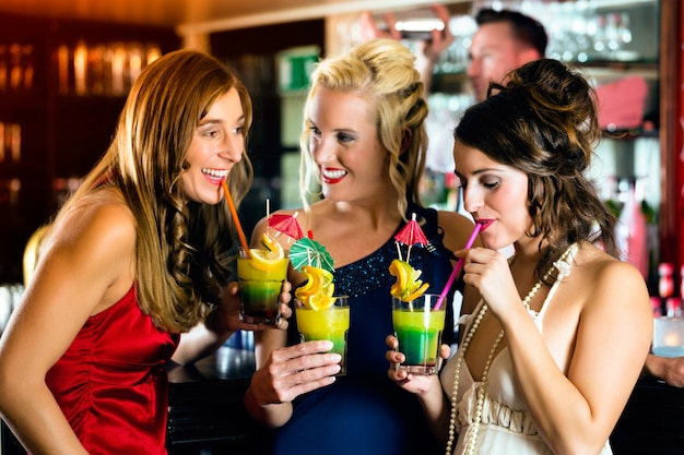 Mujeres jóvenes en bar o club divirtiéndose y riendo