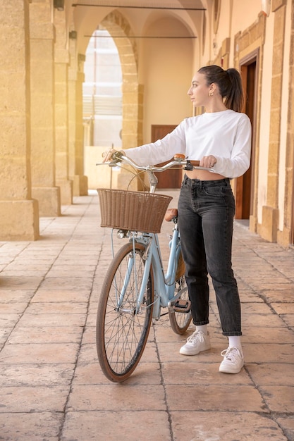 Las mujeres jóvenes con bicicleta mirando a otro lado en una pequeña ciudad