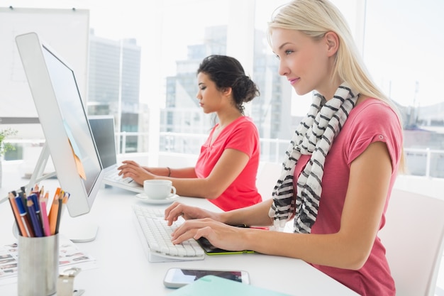 Mujeres jóvenes casuales que usan las computadoras en la oficina