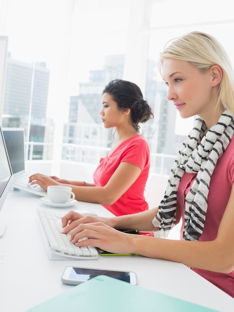 Mujeres jóvenes casuales que usan las computadoras en la oficina