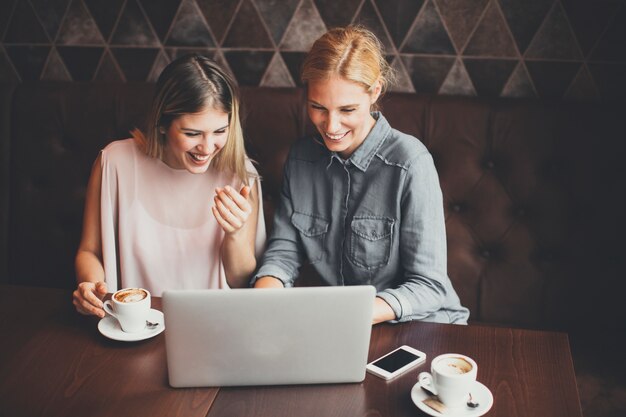 Mujeres jóvenes con computadora portátil en el café