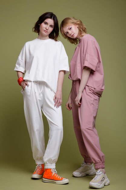 mujeres jóvenes elegantes con traje deportivo blanco y rosa, estilo de caminar sobre fondo verde