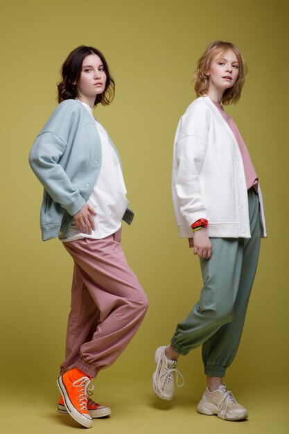 mujeres jóvenes elegantes con traje deportivo blanco, rosa y verde menta sobredimensionado, chaqueta, estilo de caminar