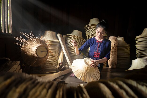 Las mujeres jóvenes están tejiendo en la canasta artesanal de Tailandia.