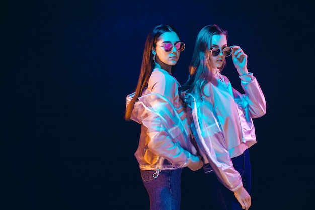 Mujeres jóvenes con estilo posando en luz de neón