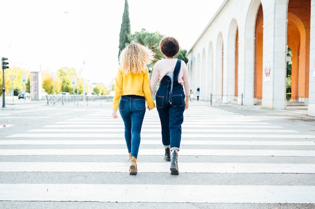 Mujeres jovenes con estilo que tienen reunión amistosa que camina en la calle. Concepto LGTB