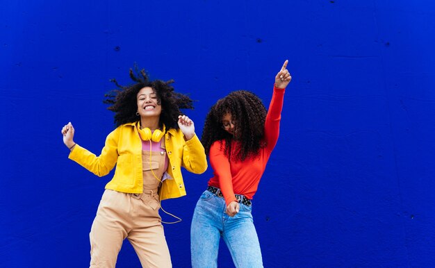 Mujeres jóvenes felices bailando y divirtiéndose al aire libre