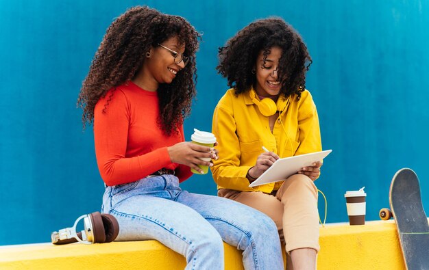 Mujeres jóvenes felices estudiando en un dispositivo de tableta