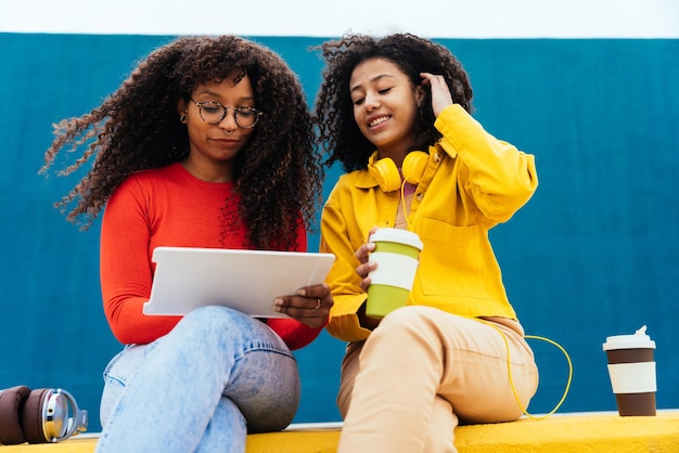 Mujeres jóvenes felices estudiando en un dispositivo de tableta