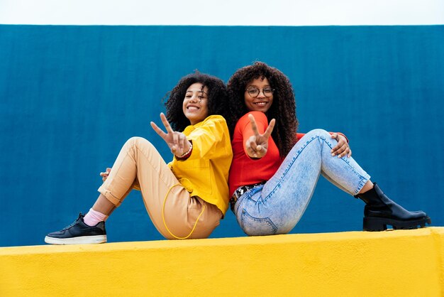 Mujeres jóvenes felices posando en paredes de color azul y amarillo