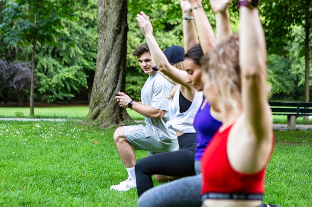 Foto mujeres jóvenes haciendo ejercicio con su entrenador de fitness en un parque de múnich