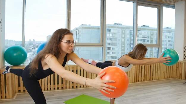 Mujeres jóvenes haciendo fitness en el estudio sosteniendo una pelota