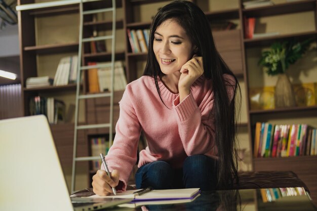 Foto mujeres jóvenes y hermosas toman nota mientras trabajan desde casa.