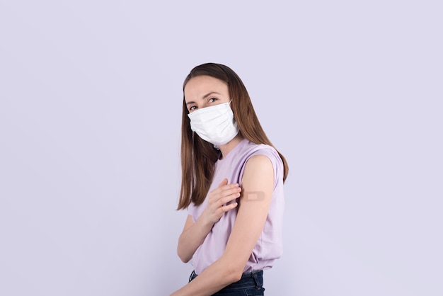 Mujeres jóvenes en máscara con vendaje adhesivo después de la vacunación sonriendo