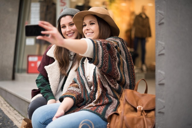 Mujeres jóvenes de moda tomando selfies en la ciudad