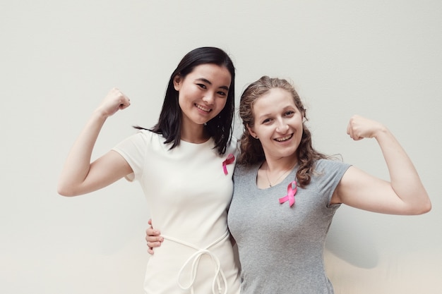 Foto mujeres jóvenes multiculturales con cintas rosas.