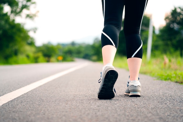 Las mujeres jóvenes se preparan para caminar o trotar en un camino rural. Vista posterior de piernas femeninas. Concepto de cuidado de la salud con ejercicio.