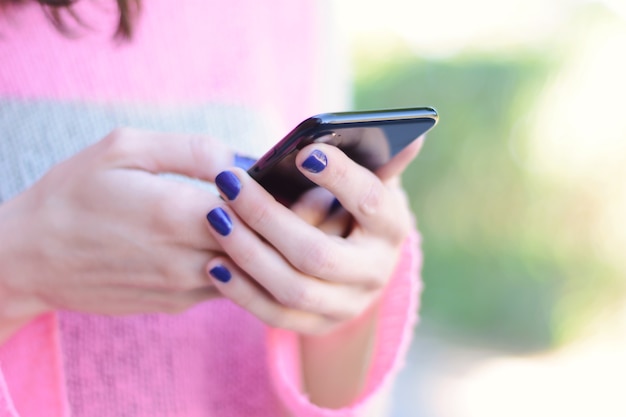 Las mujeres jóvenes que envían el mensaje con el teléfono inteligente.