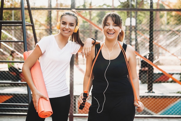 Mujeres jóvenes riendo mientras hacen deporte con su amiga en la mañana