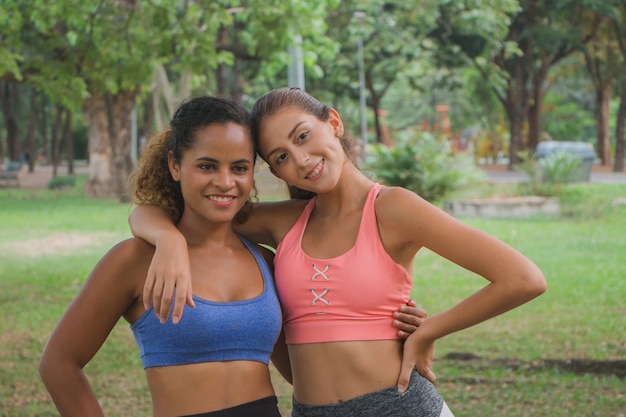 Mujeres jóvenes sanas que se relajan después de los ejercicios en el parque.