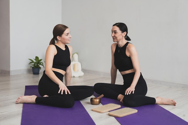 Las mujeres jóvenes se sientan en colchonetas de yoga para comenzar a practicar meditación y yoga.