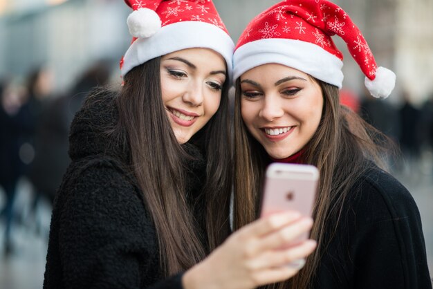 Mujeres jóvenes con sombrero de Navidad tomando una foto juntos