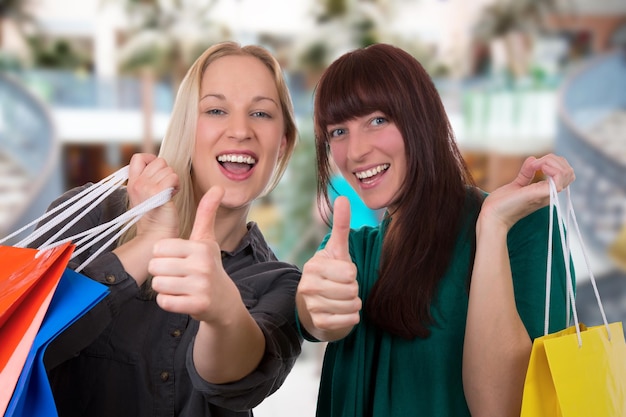 Foto mujeres jóvenes sonrientes divirtiéndose mientras compran en un centro comercial