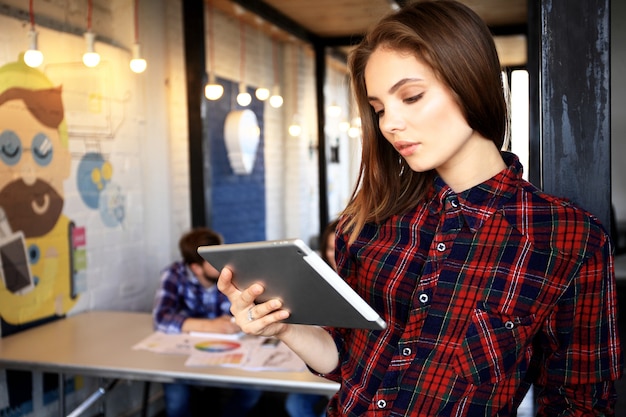 Mujeres jóvenes sonrientes con tableta digital en la oficina.