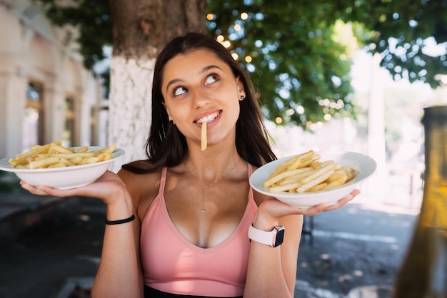 Mujeres jóvenes sostienen papas fritas en platos blancos Street cafe