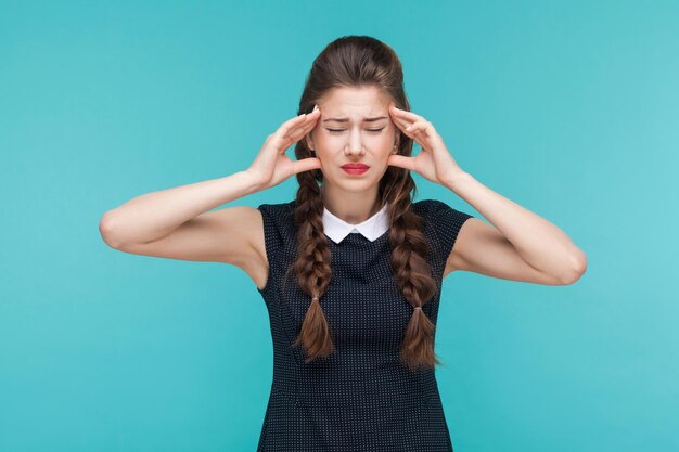 Las mujeres jóvenes tienen migraña y dolor de cabeza. tiro del estudio, fondo azul