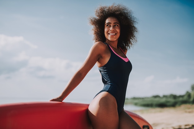 Mujeres jóvenes en traje de baño Lean On Surf en la playa.