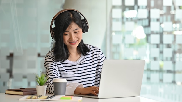 Mujeres jóvenes usando laptop y escuchando canciones en auriculares