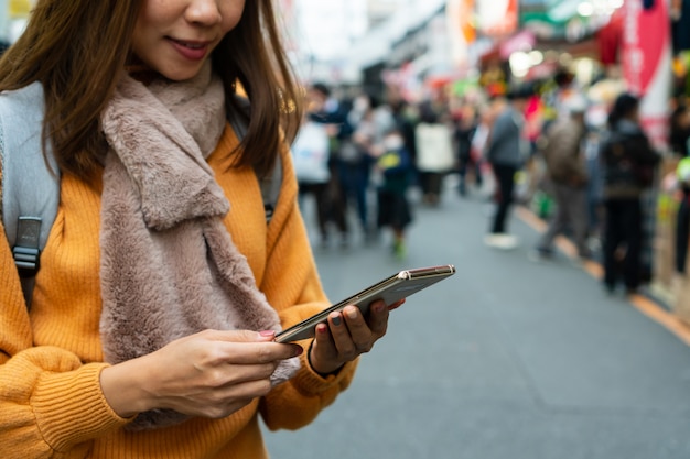 Mujeres jóvenes viajeros que usan teléfonos inteligentes para buscar el mapa en el mercado callejero