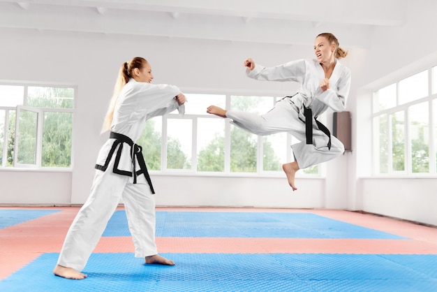 Mujeres jóvenes vistiendo kimono y cinturón negro de entrenamiento de artes marciales de karate.