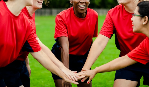 Mujeres jugadoras de rugby apilando sus manos juntas