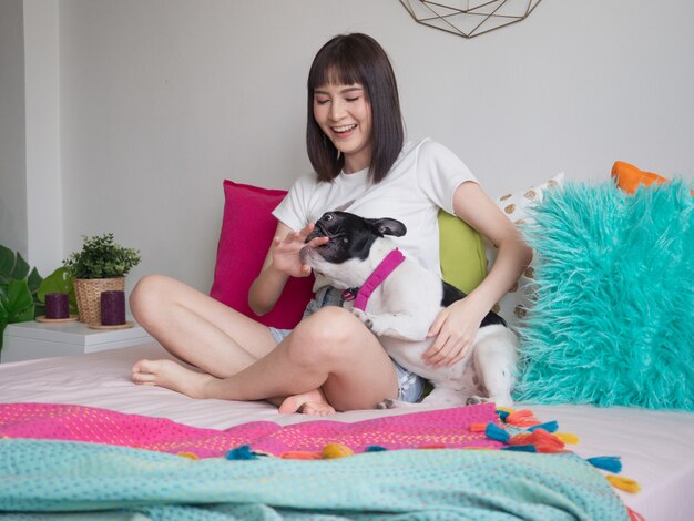 Mujeres jugando con perros en la cama.