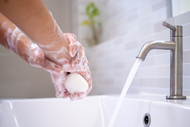 Las mujeres se lavan las manos con jabón en los lavabos del baño.