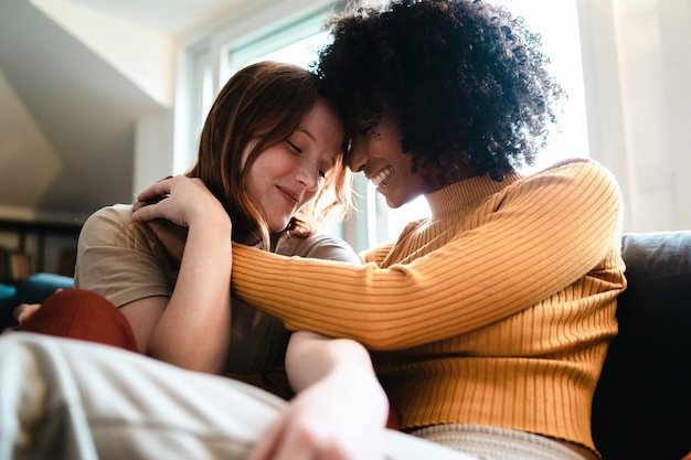 Mujeres lesbianas acariciándose en el sofá. Pareja de chicas homosexuales coqueteando en el sofá. Concepto de equidad de género.