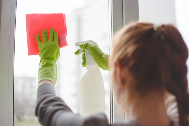 Foto mujeres limpiando una ventana con spray y tela. de cerca