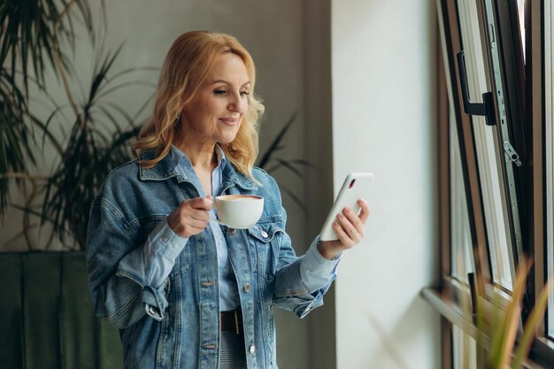 Mujeres maduras que usan un teléfono en un café