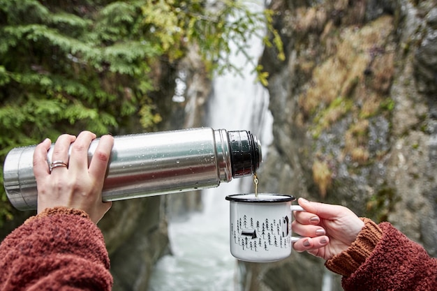 Foto mujeres con la mano sosteniendo una taza de té al aire libre en clima frío explorando la naturaleza