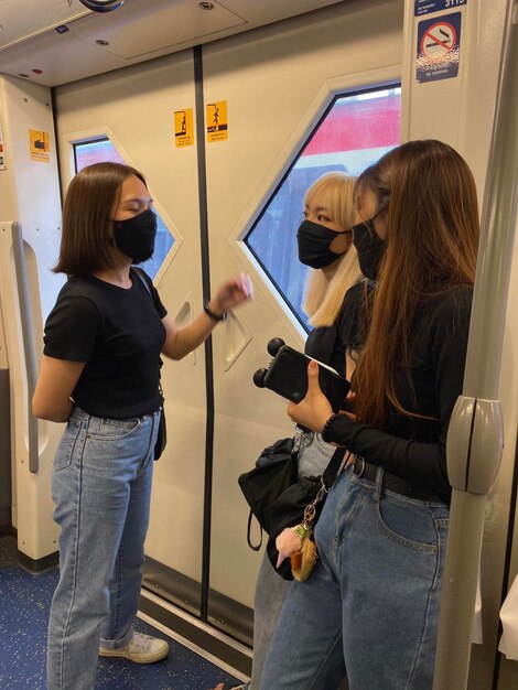 Foto mujeres con máscaras de toda la longitud de pie en el tren
