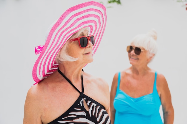 Mujeres mayores felices que tienen fiesta en la piscina - Amigos mayores relajándose en una fiesta en la piscina
