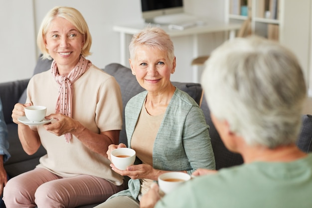 Las mujeres mayores hablando entre sí para una taza de té en casa