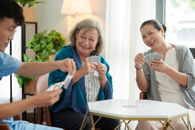 Mujeres mayores jugando a las cartas con la enfermera