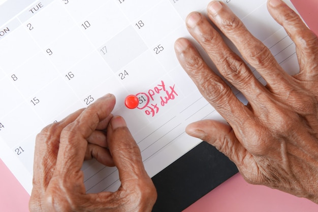 Las mujeres mayores con la mano en el calendario apuntando a pagar la deuda texto